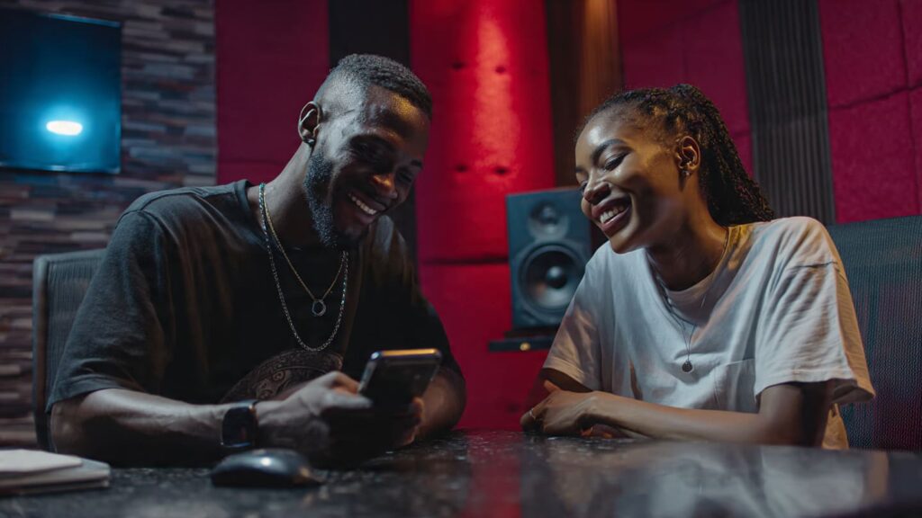 Two Nigerian entrepreneurs in a creative workspace using guest host Instagram live growth tactics to merge their audiences.