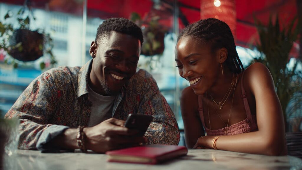 Two young Nigerians in a Lagos cafe collaborating to scale Instagram profile clicks through meaningful community engagement.