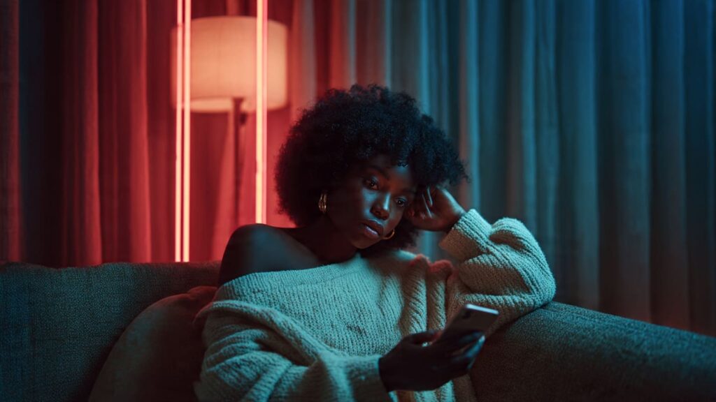 Frustrated Nigerian female creator analyzing low reach on her smartphone screen in a modern Lagos home.