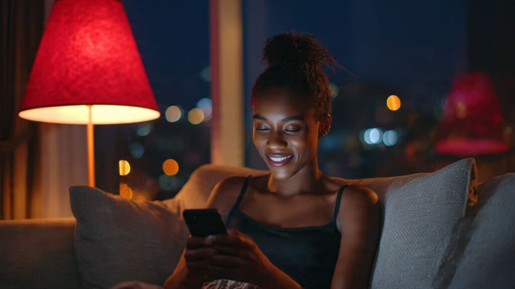 A Nigerian woman scrolling her phone during the 7 PM rush to get more Instagram profile views during peak hours.