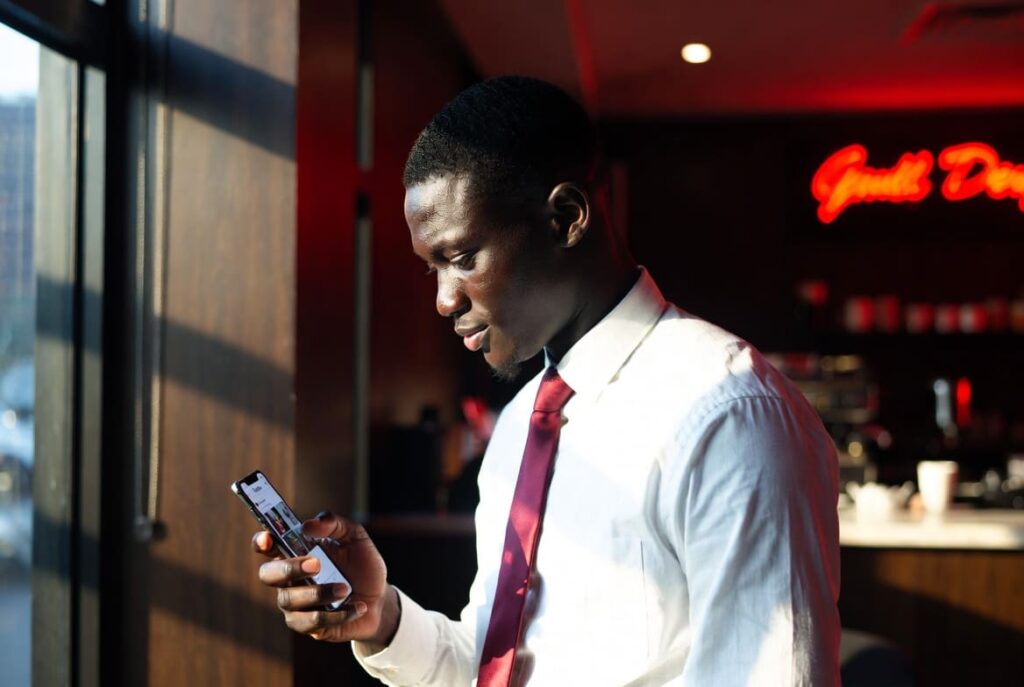 A group of Nigerian friends laughing while learning how to make reels shareable in Nigeria on a smartphone screen.