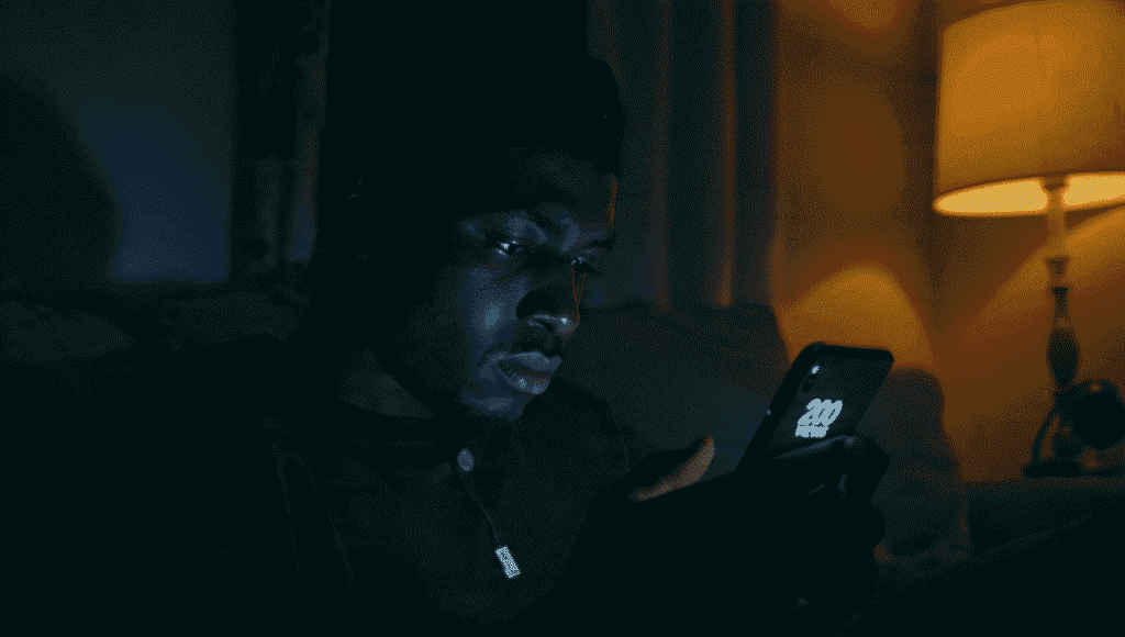 Frustrated Nigerian creator looking at a phone with low engagement metrics on an Instagram Reel.