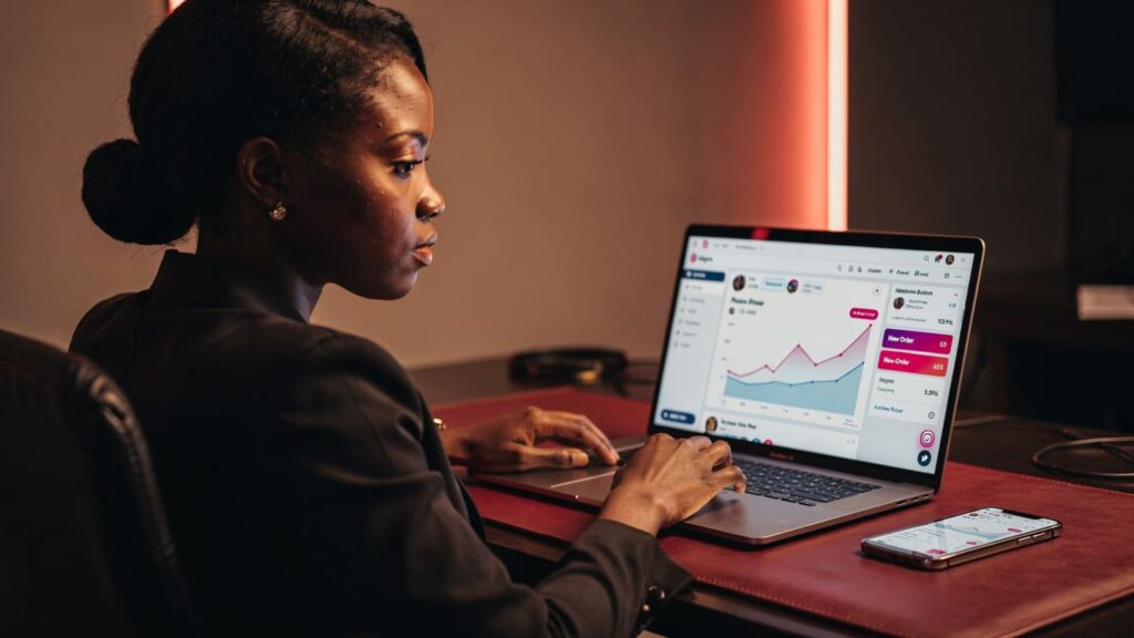 Nigerian woman looking at a laptop screen showing SMM panels Instagram growth analytics.